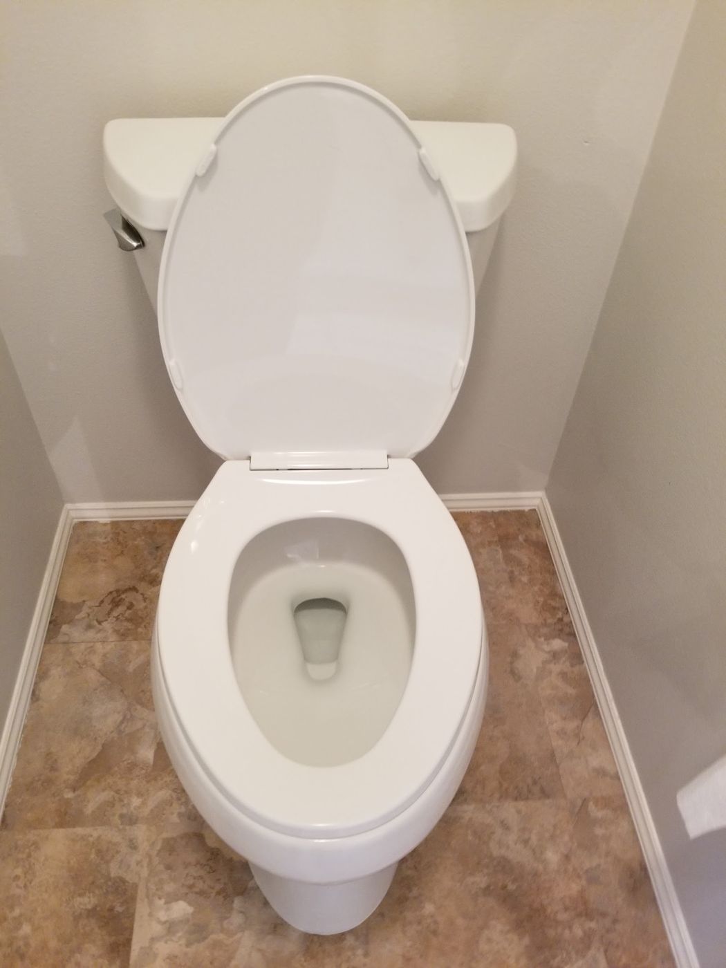 Clean toilet on a tan tile floor